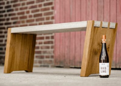 Schräge Sitzbank aus Beton und Eiche mit Weinflasche