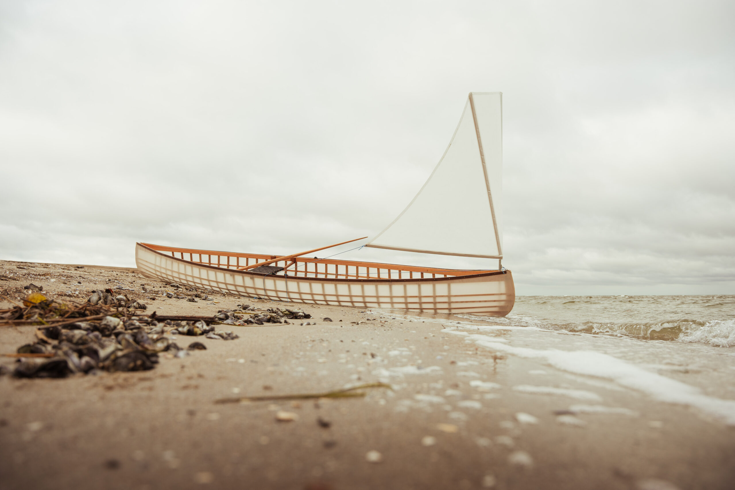 Skin-on-frame Kanu mit Segel am Strand
